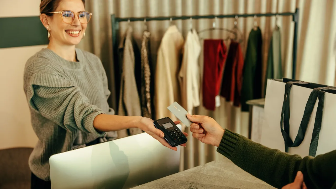 Dependienta cobrando con datáfono a un cliente en una tienda de moda